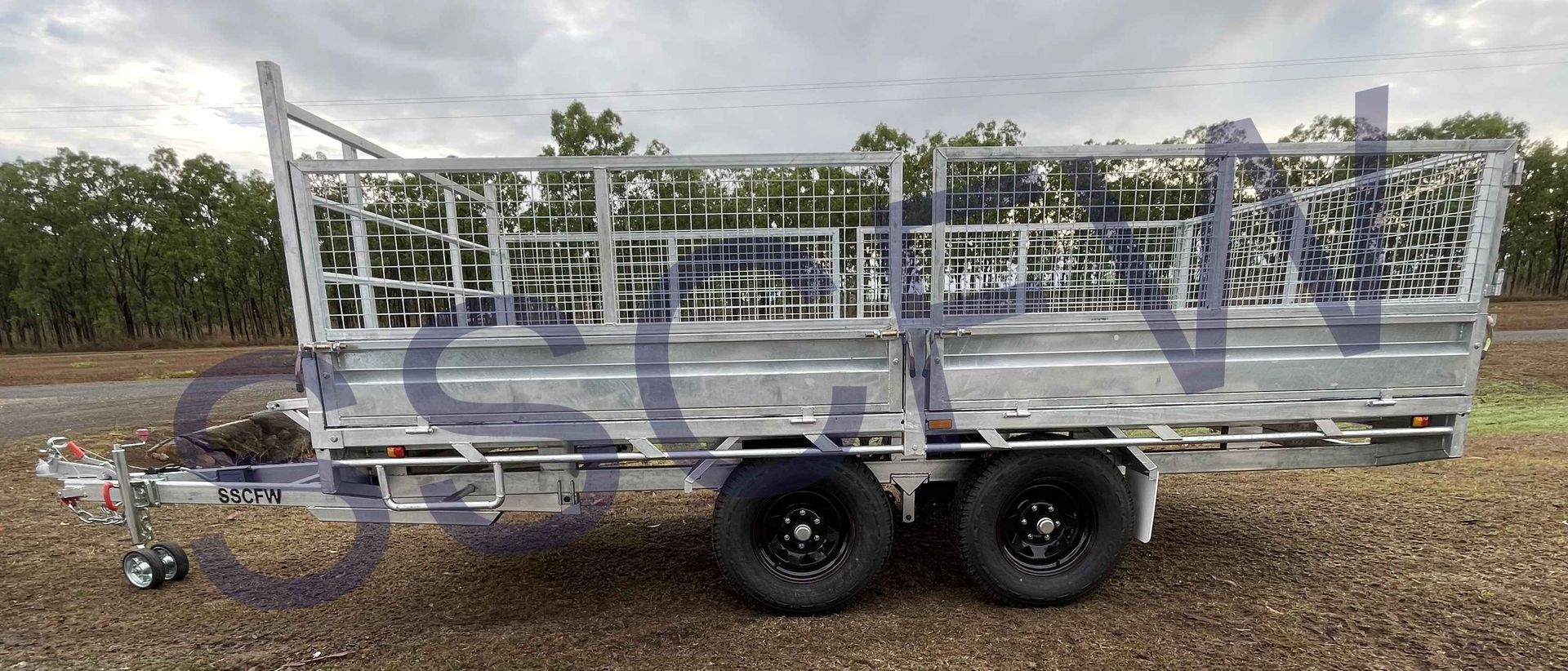 A trailer with a fence on it is parked on the side of the road.