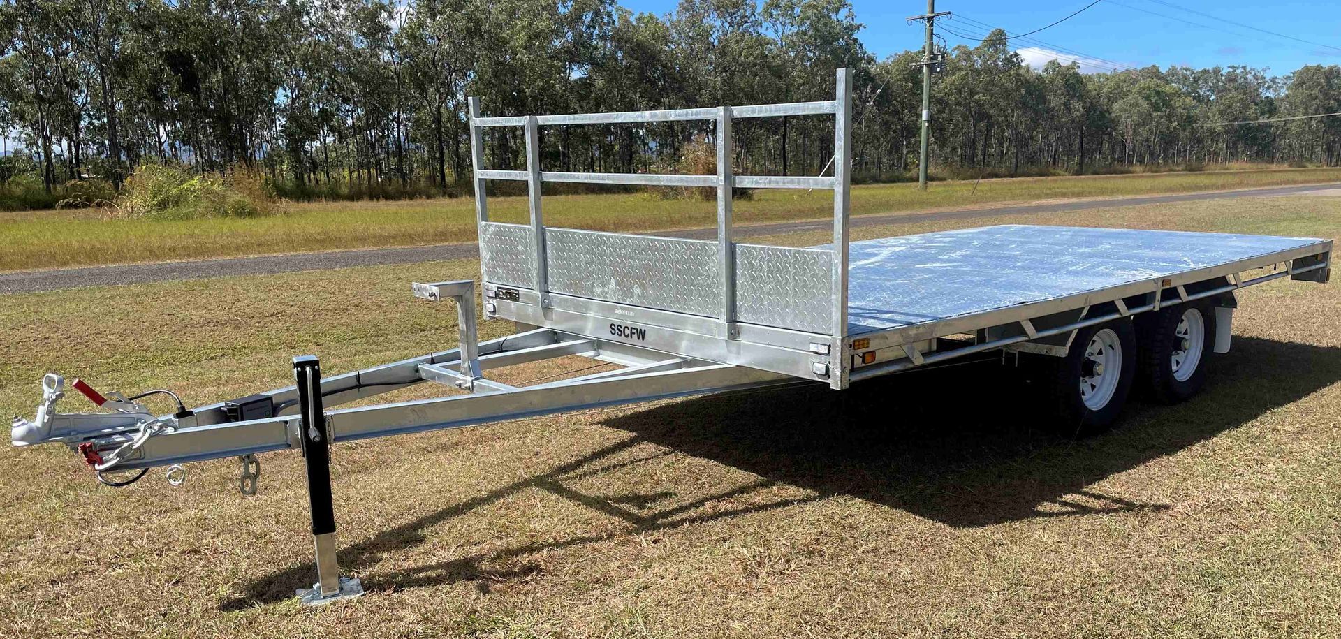 A flatbed trailer is parked in a grassy field.