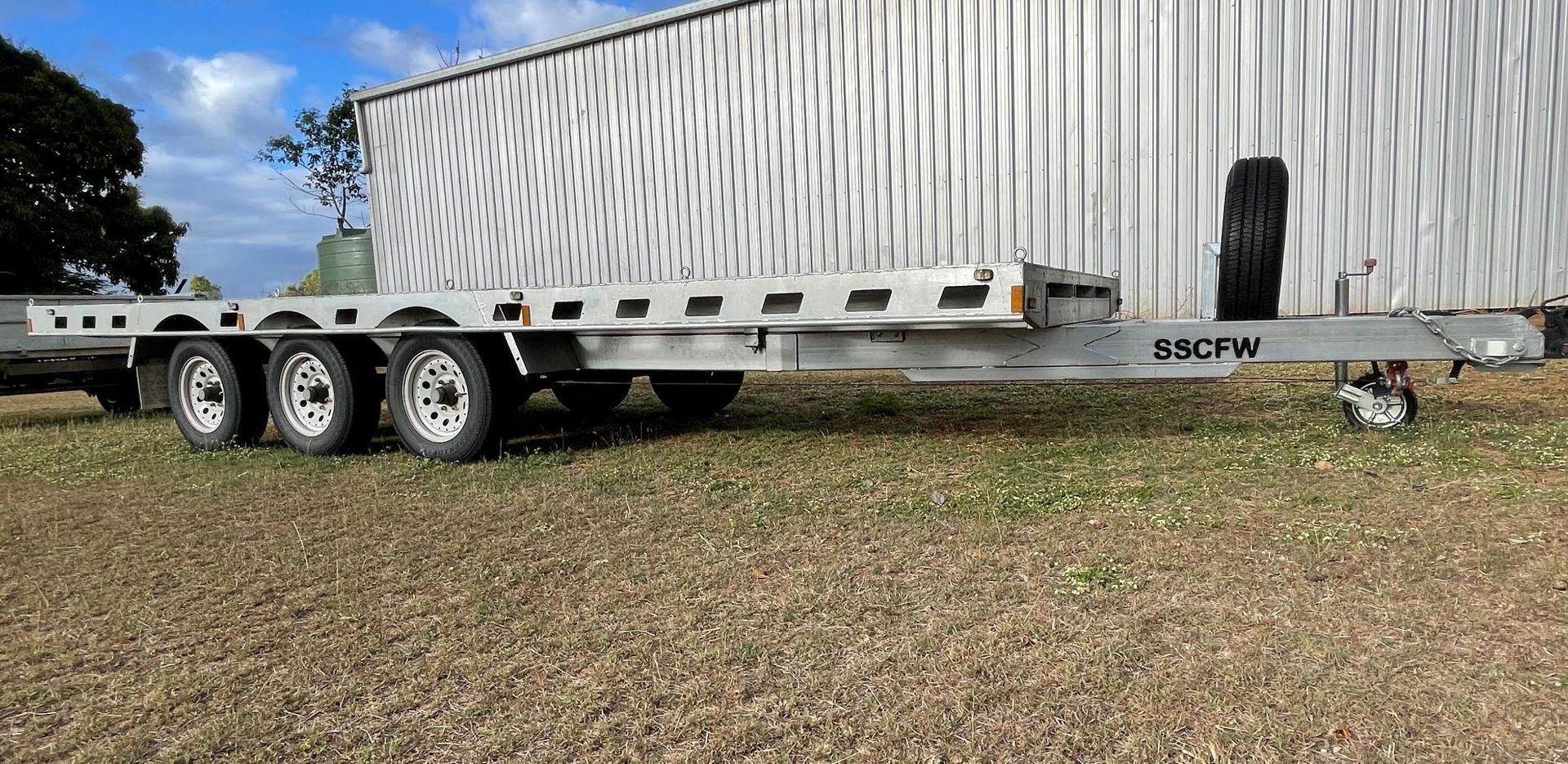 A trailer is parked in a gravel lot in front of a building.