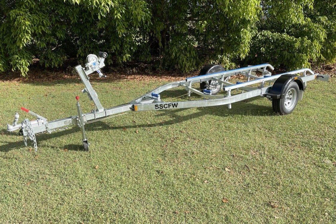 A boat trailer is sitting on top of a lush green field.