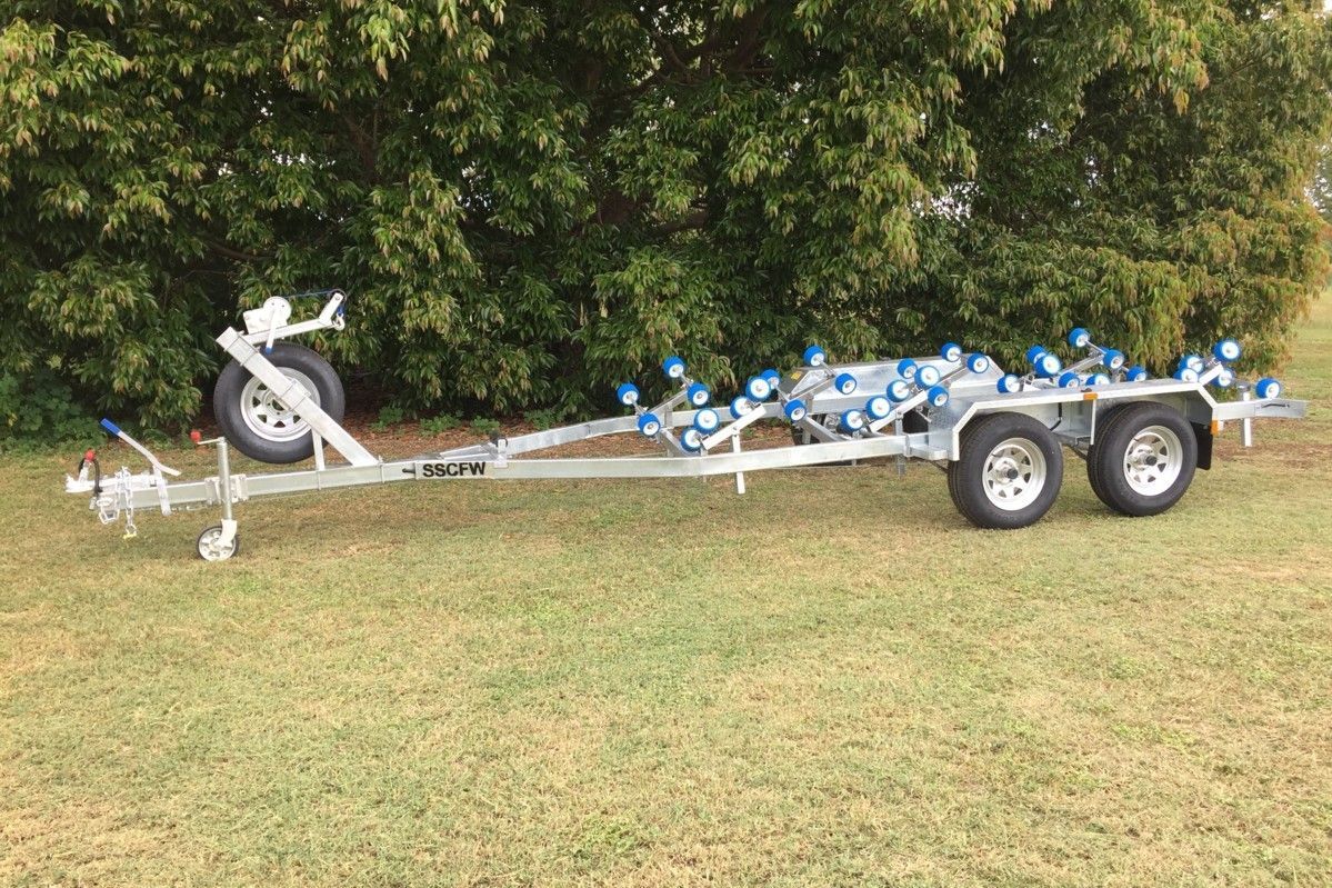 A boat trailer is sitting on top of a lush green field.