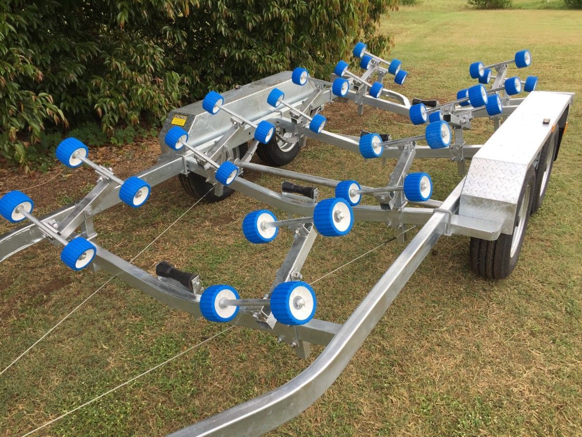 A boat trailer with blue wheels is sitting on top of a lush green field.