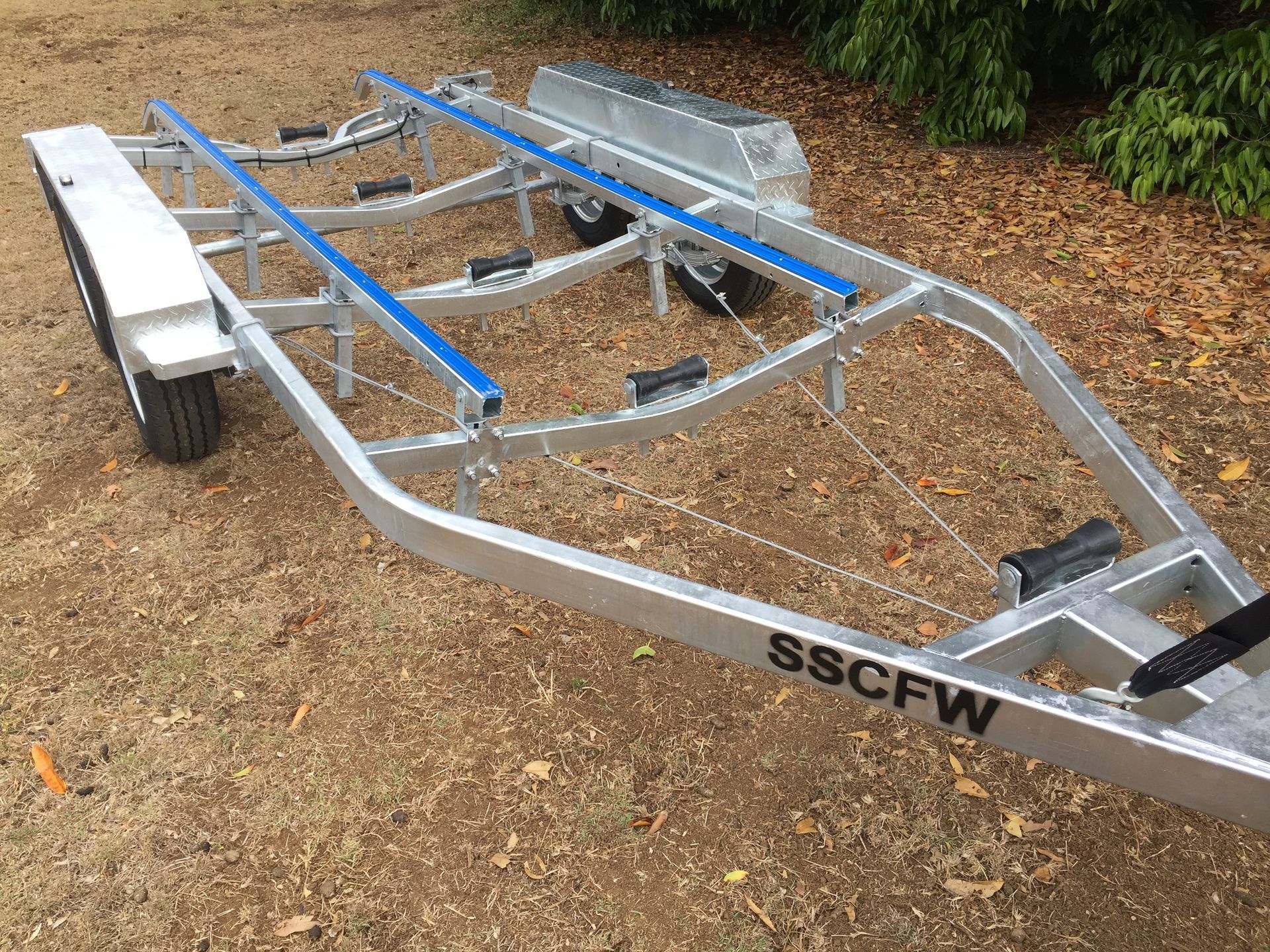 A boat trailer is sitting on top of a dirt field.