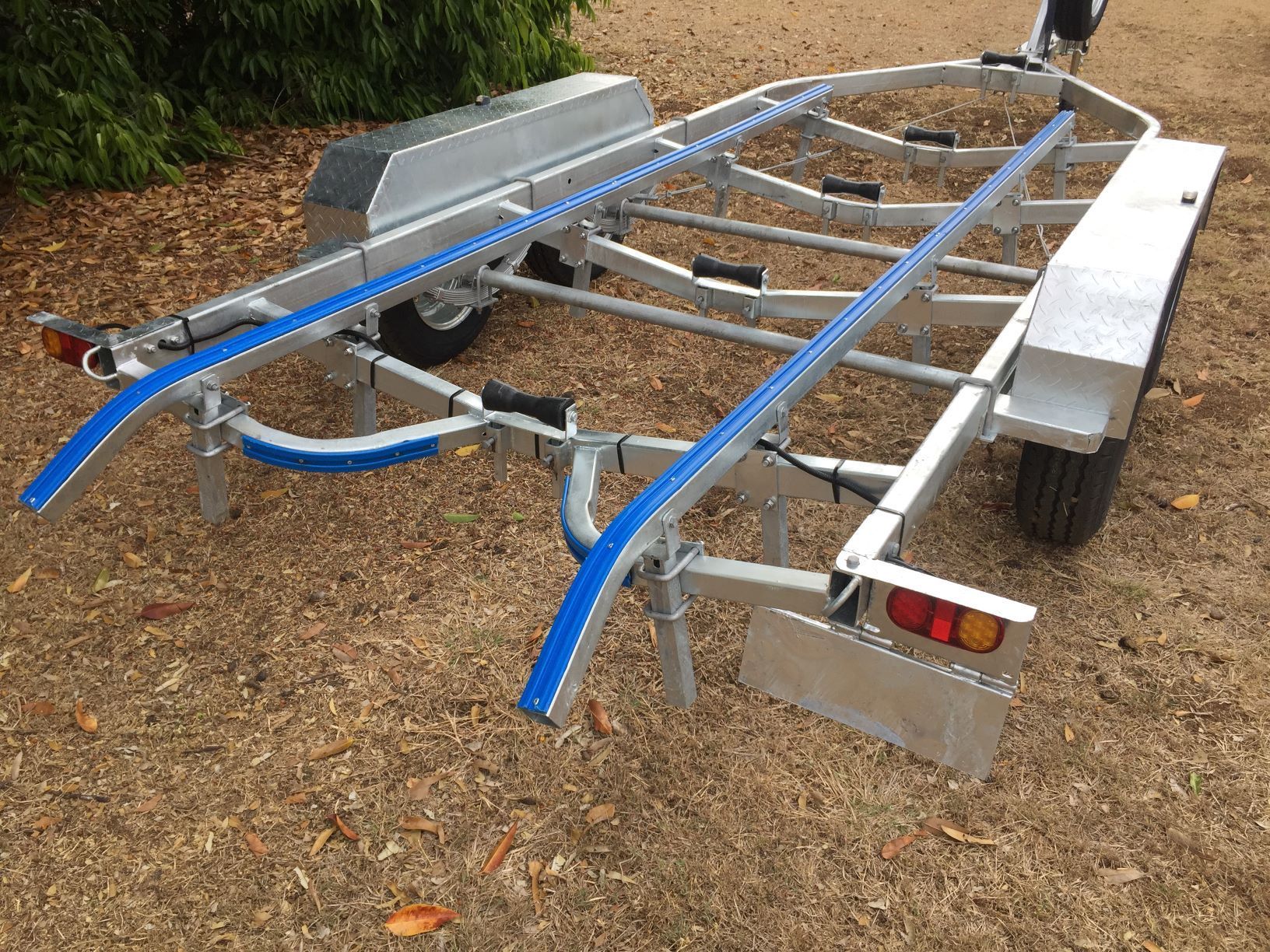 A boat trailer is sitting on top of a dirt road.