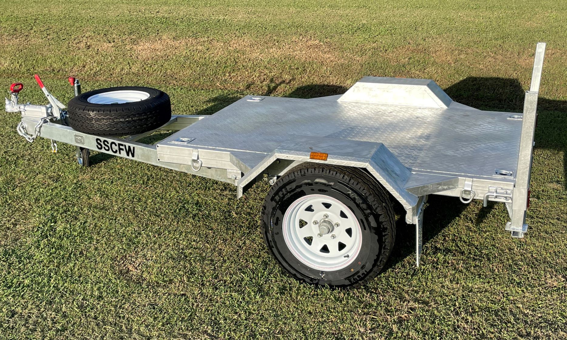 A small trailer is sitting on top of a lush green field.