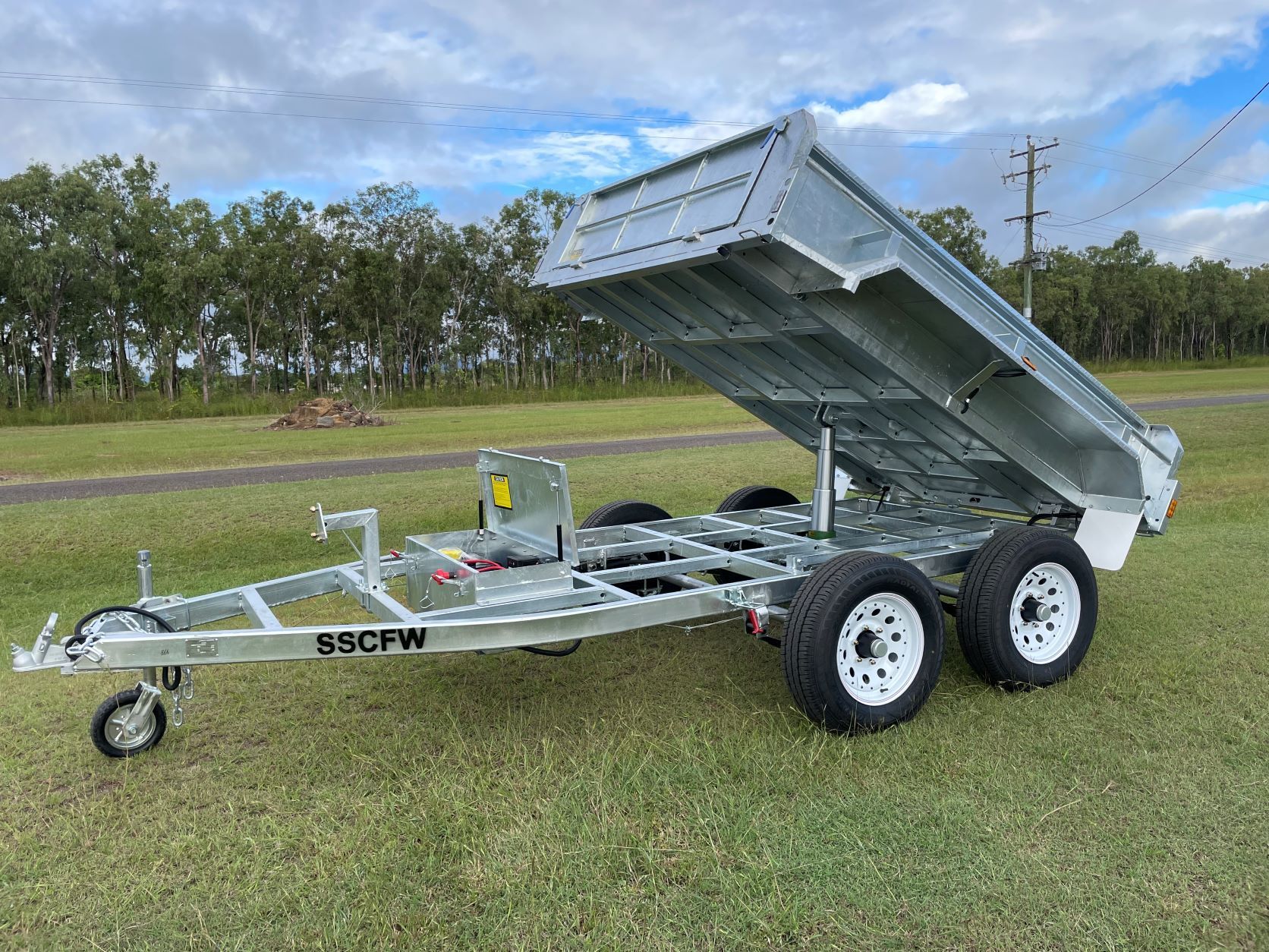 A dump trailer is sitting on top of a lush green field.