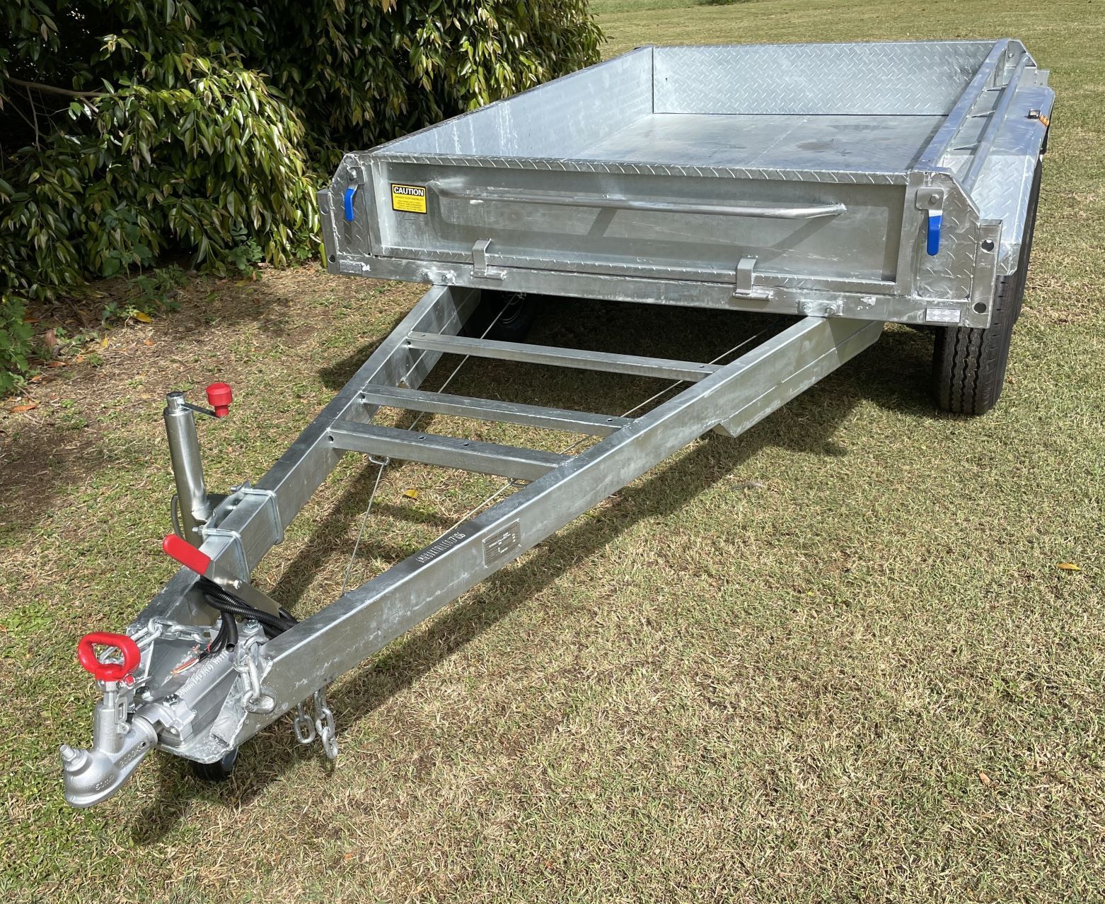 A trailer is sitting on top of a lush green field.