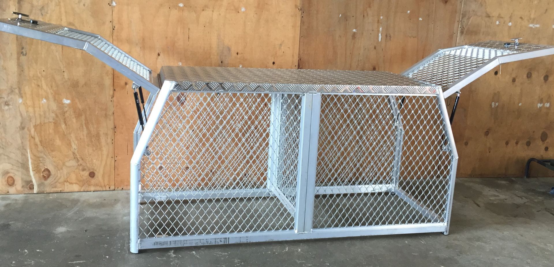 A metal cage is sitting in front of a wooden wall.