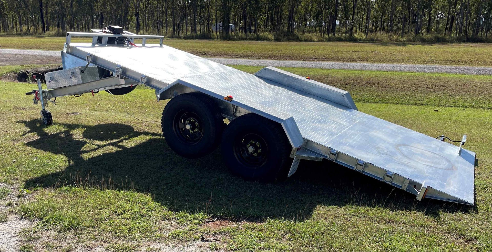 A trailer is sitting on top of a lush green field.