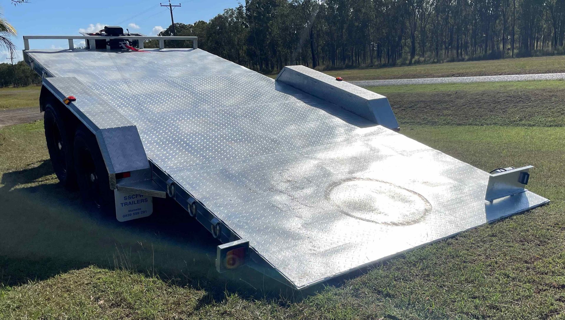 A flatbed trailer is parked in a grassy field.