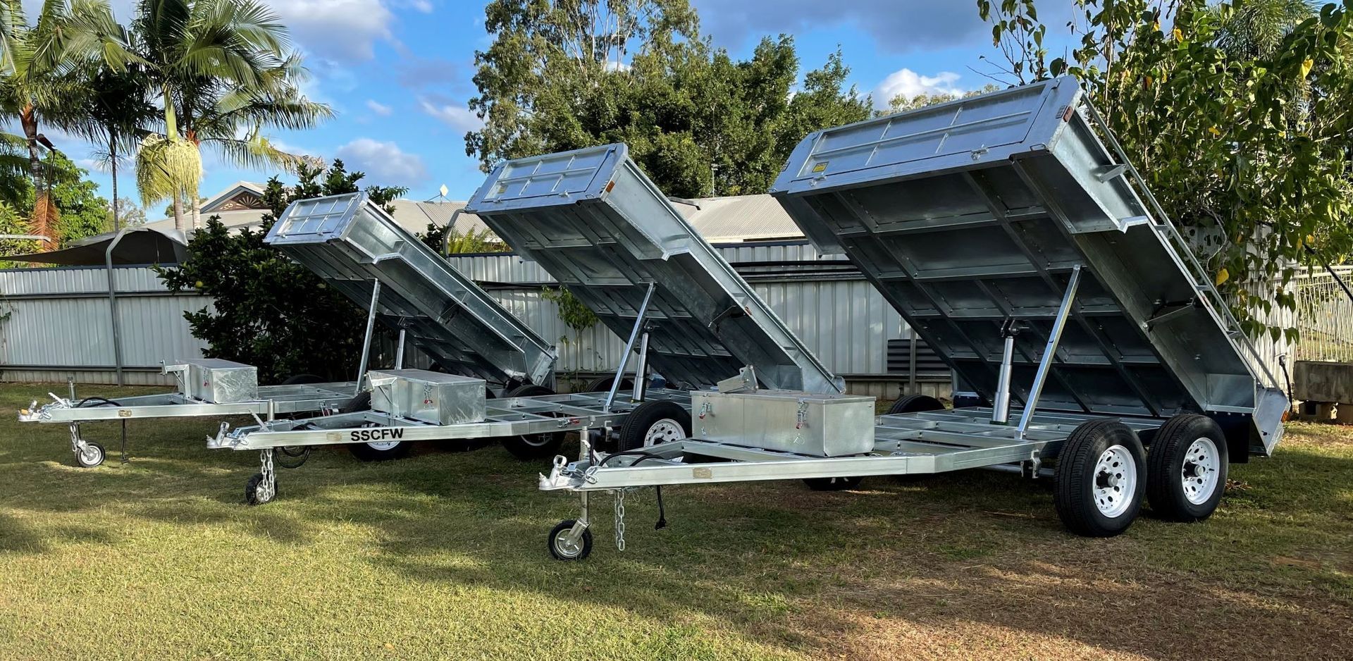 Three dump trailers are parked in a grassy field.