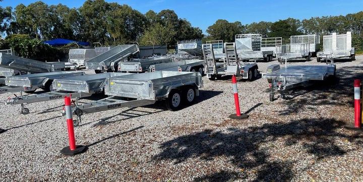 A lot of trailers are parked in a gravel lot.