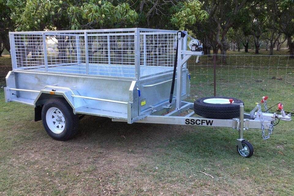 A trailer with a tire on the back is parked in the grass.