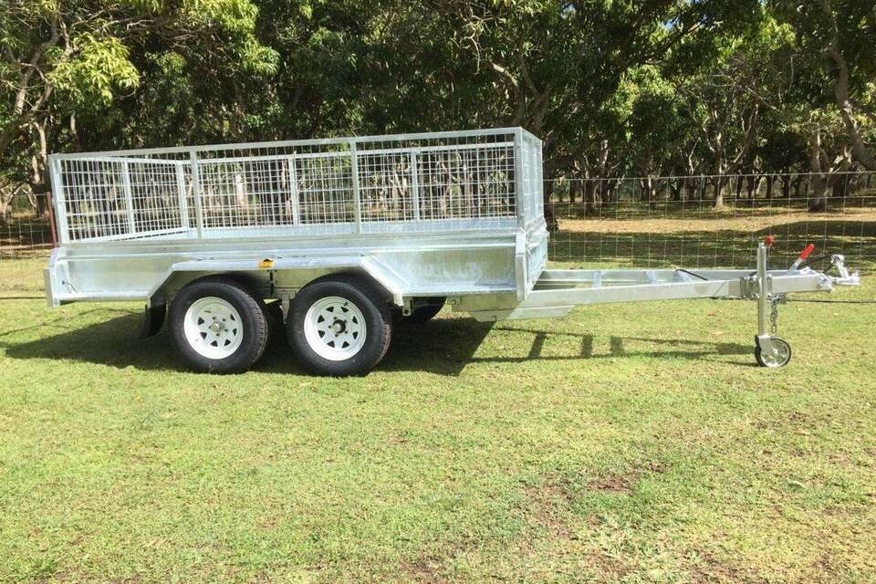 A trailer is parked in a grassy field with trees in the background.