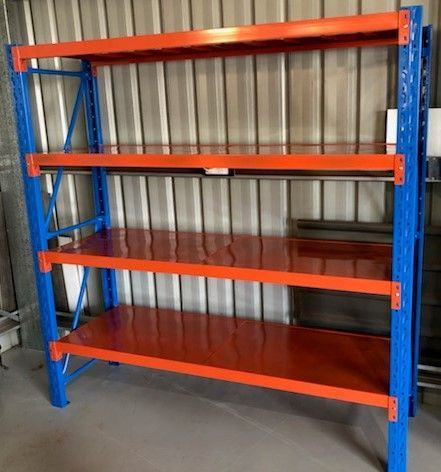 A blue and orange shelving unit is sitting in a warehouse.