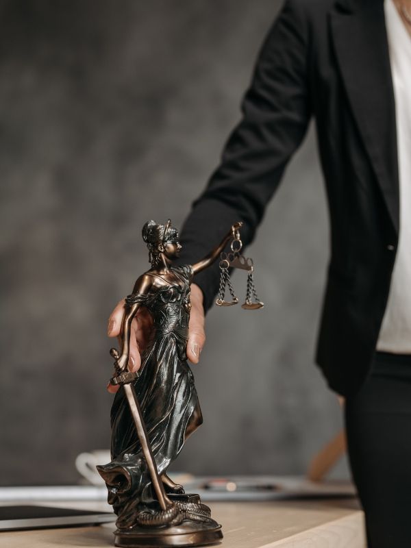 A man holds a statue of Lady Justice