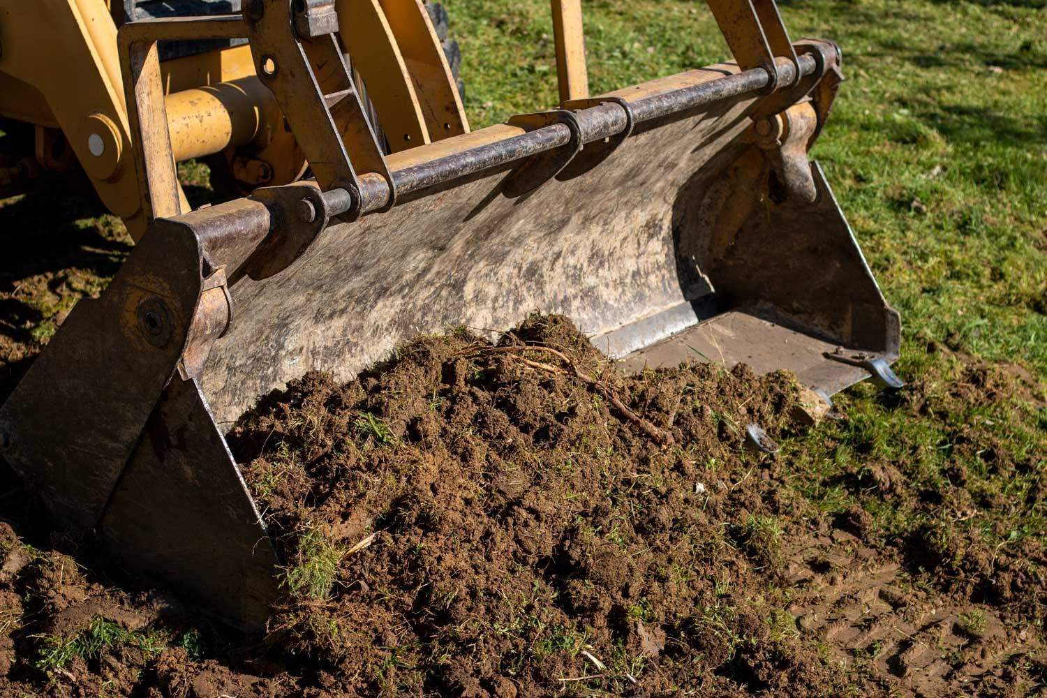 Close-up of a yellow excavator driving earth in a wide bucket, for land clearing.