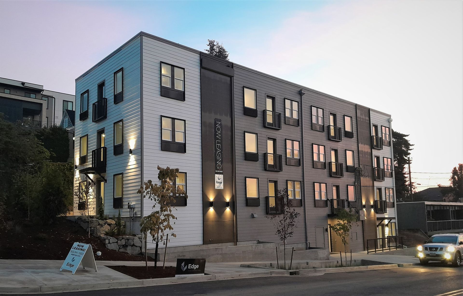 Modern multi-story apartment building with white and gray panels, and many windows.
