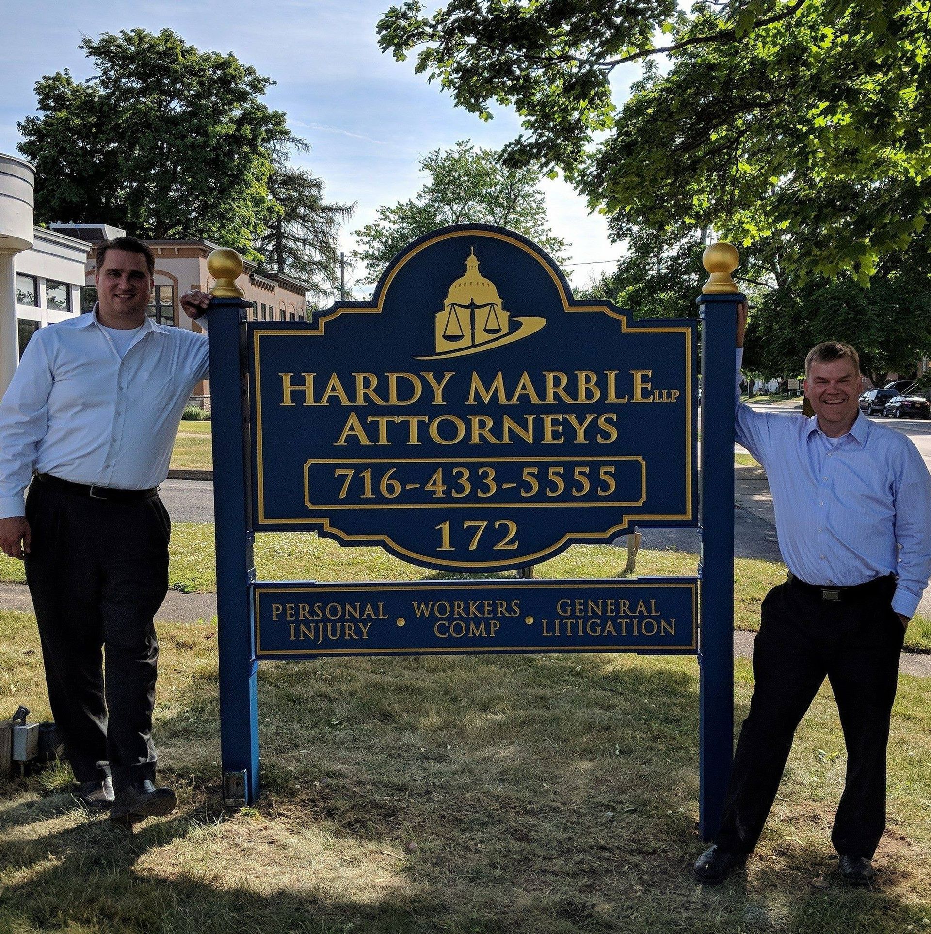 Two men standing in front of a hardy marble attorneys sign