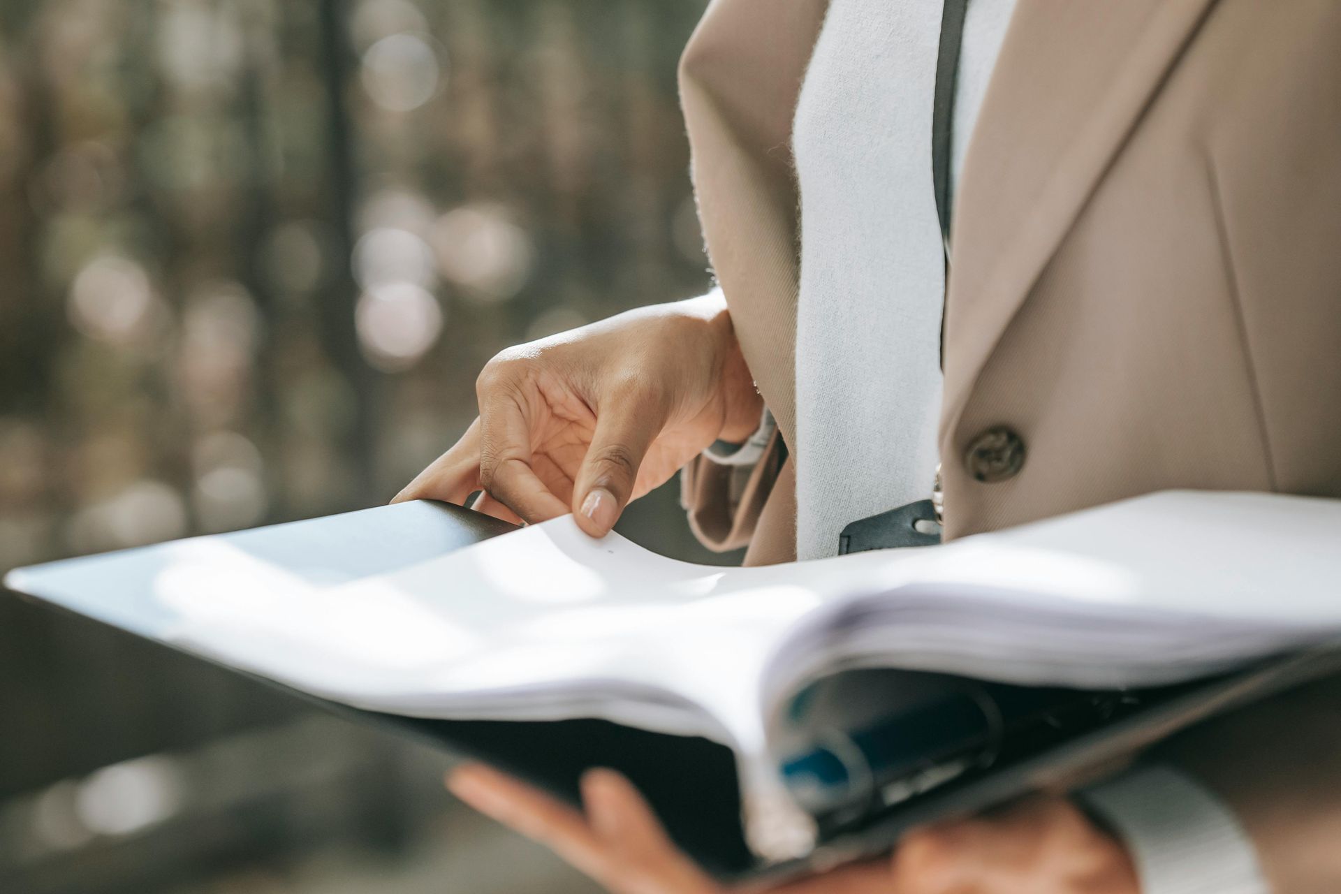 A woman in a suit and tie is holding a book and pointing at it.