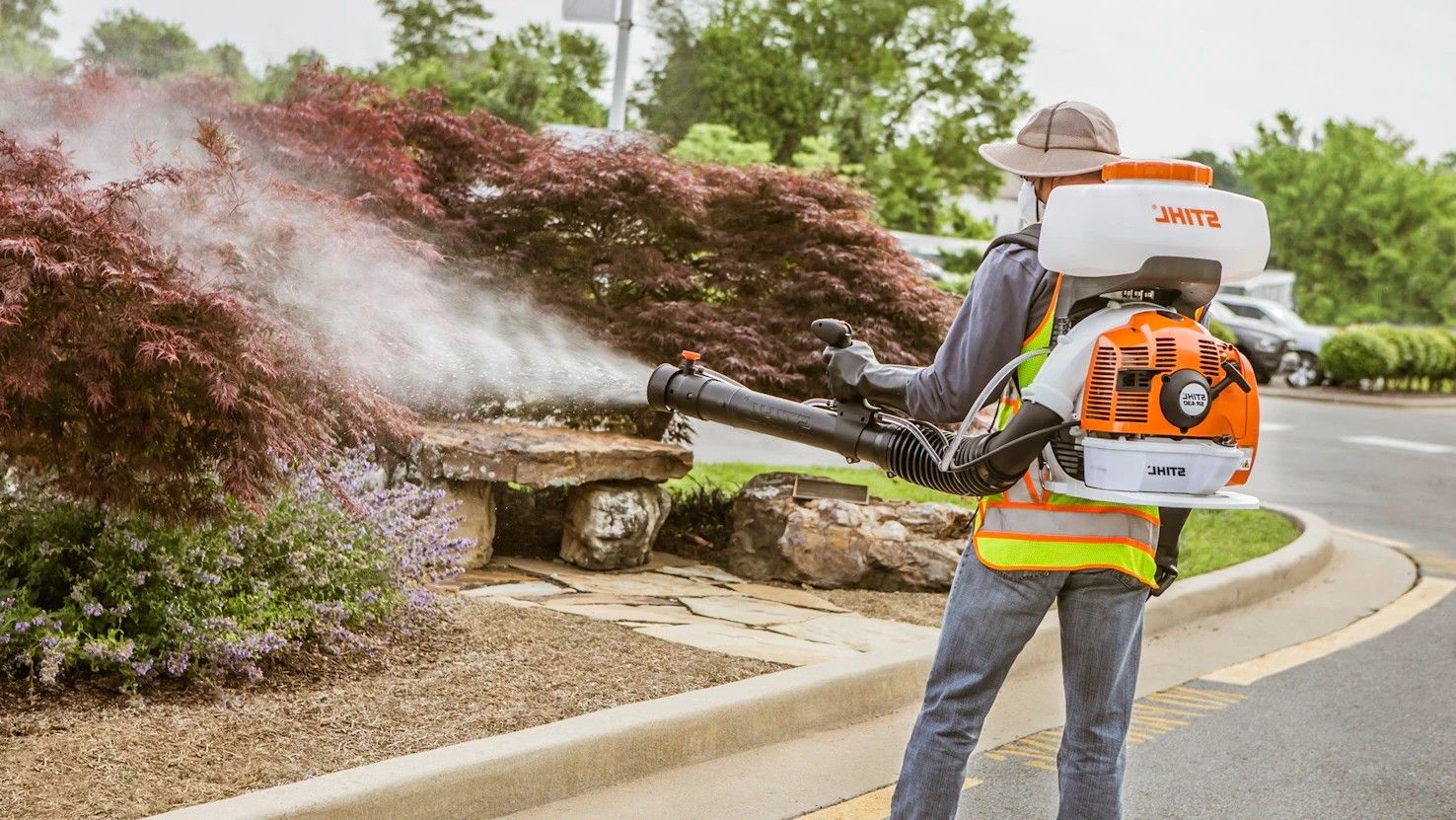 A man is spraying a tree with a backpack sprayer.