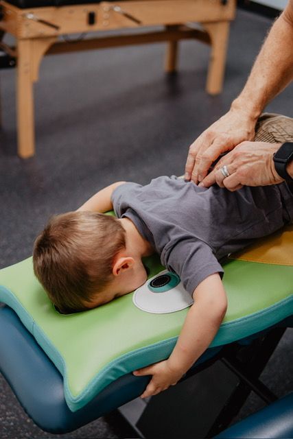 A young boy is laying on a table getting his back examined by a doctor.