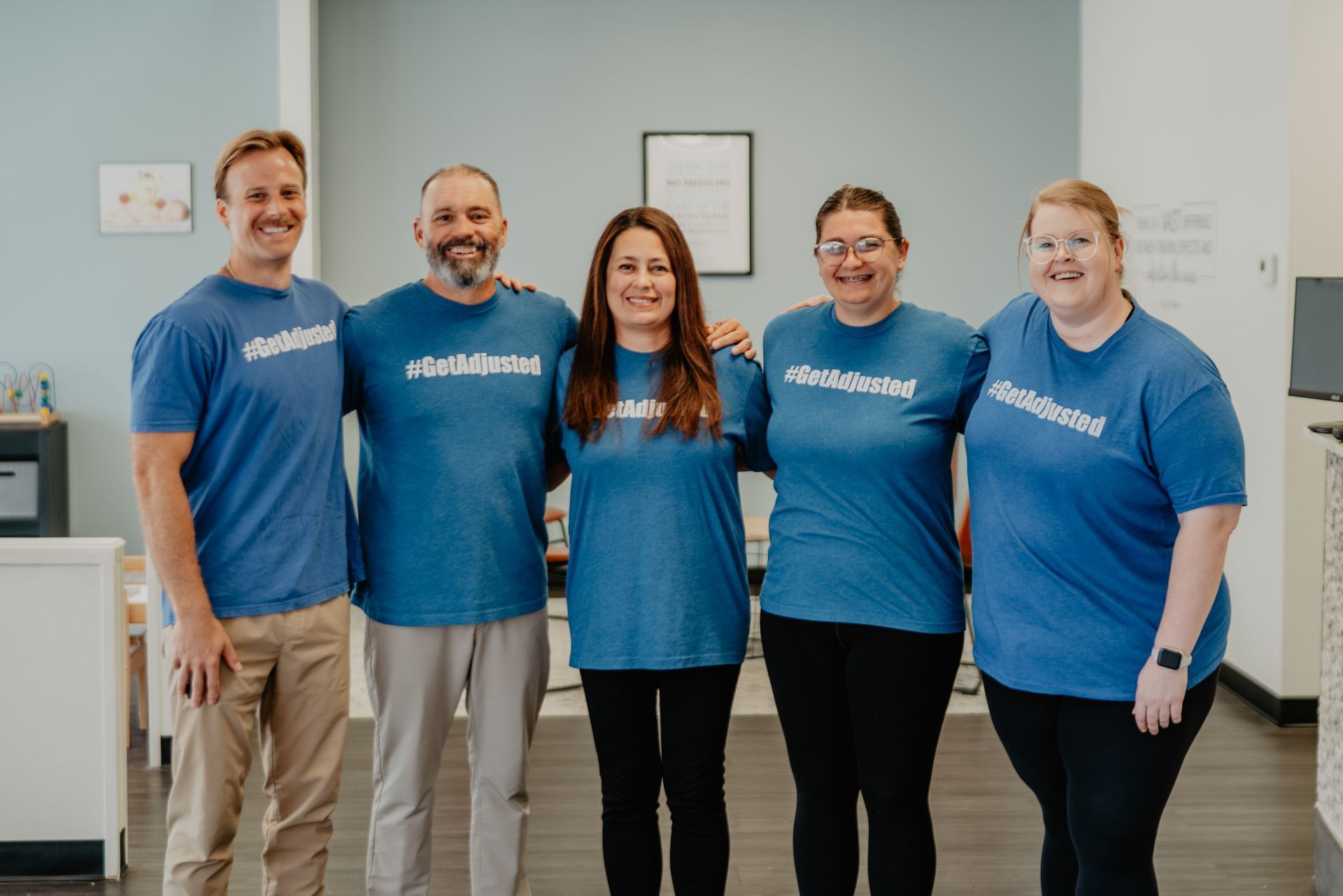 A man and a woman are posing for a picture wearing shirts that say getadjusted
