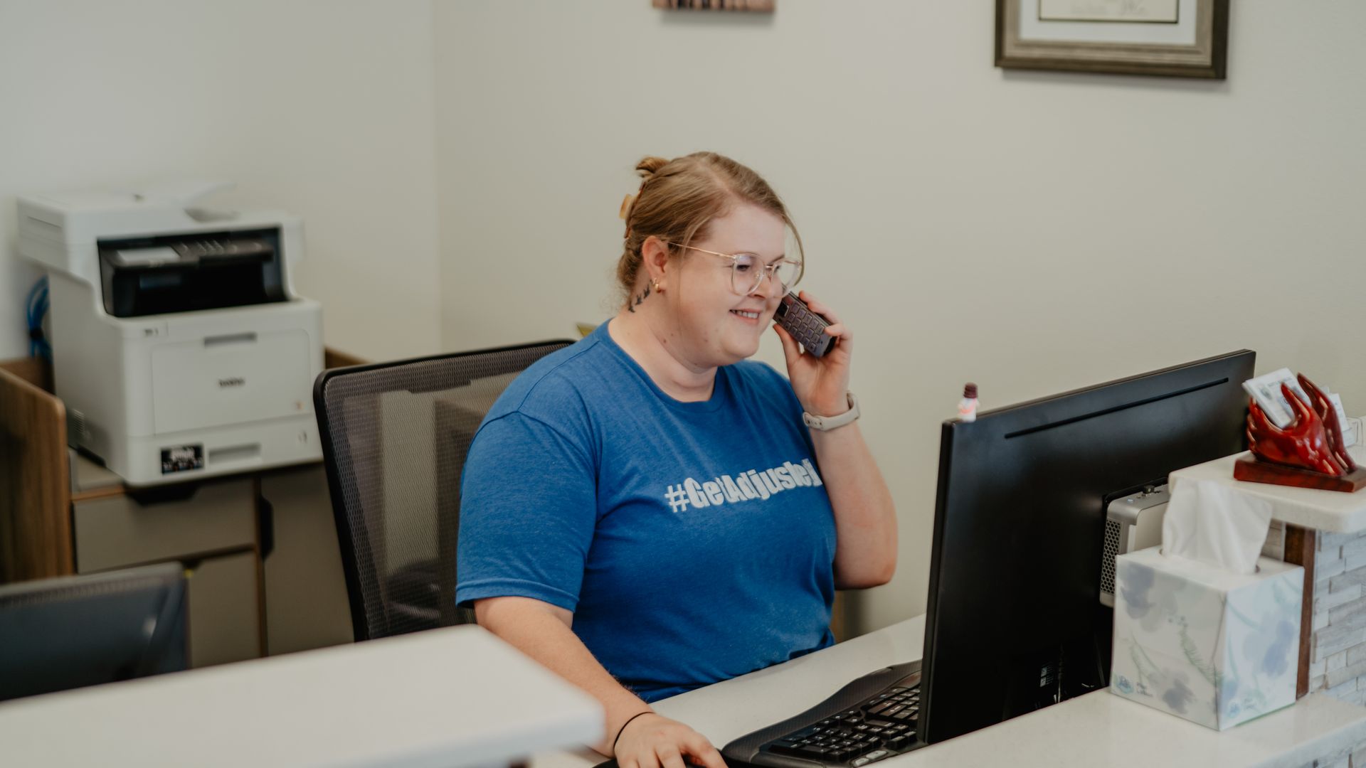 A woman is sitting at a desk in front of a computer.
