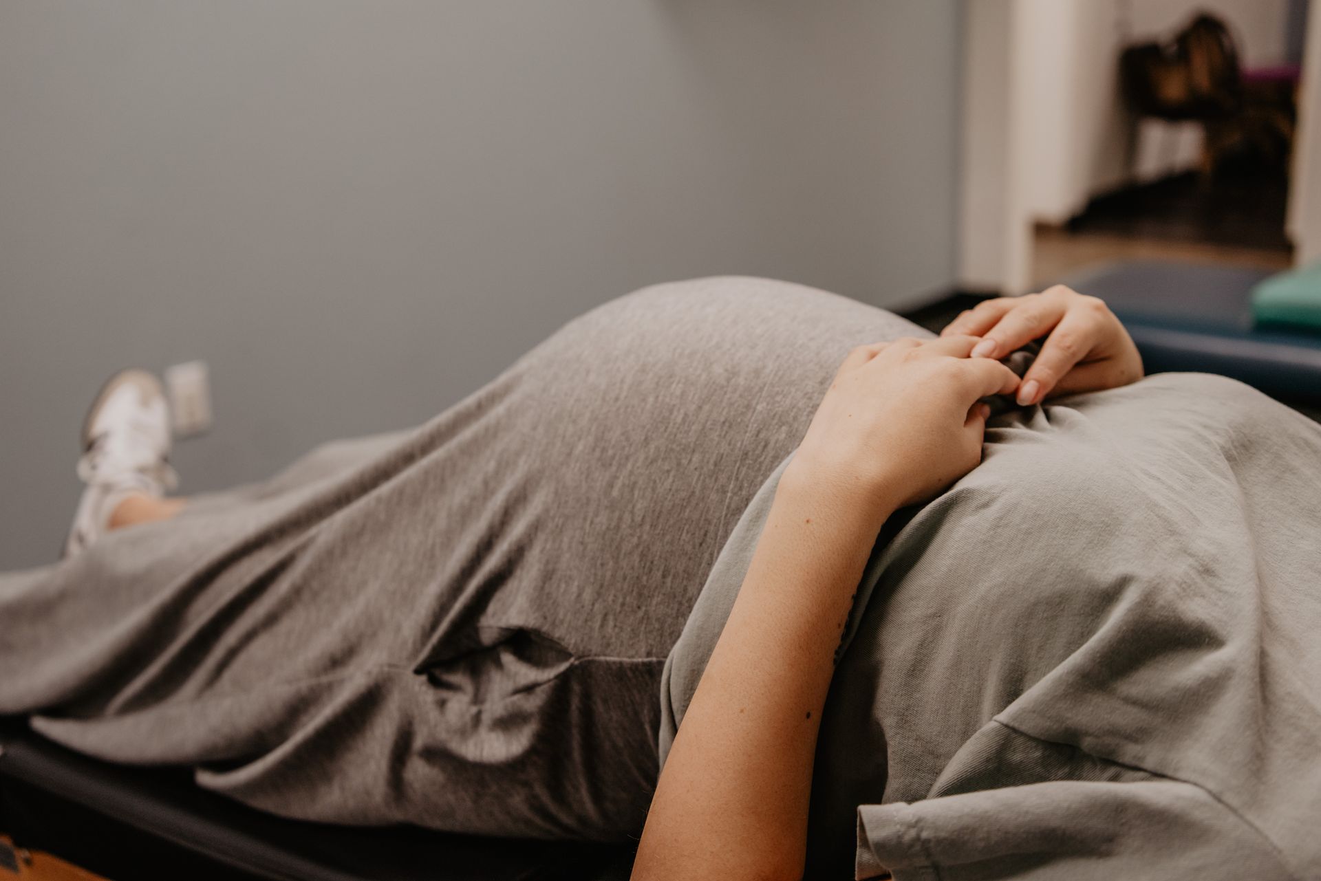 A man is sitting on a stool while a child is laying on a table.