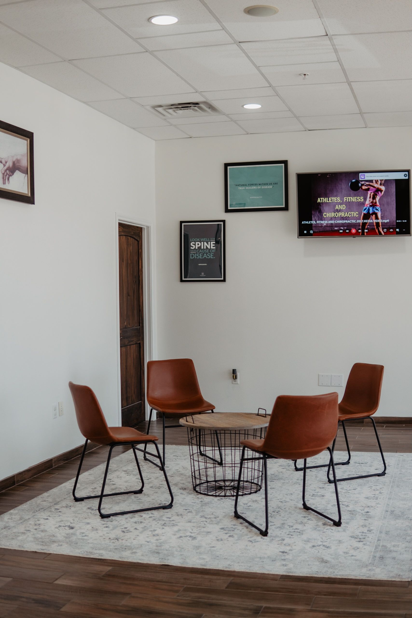 A waiting room with a table and chairs and a television.