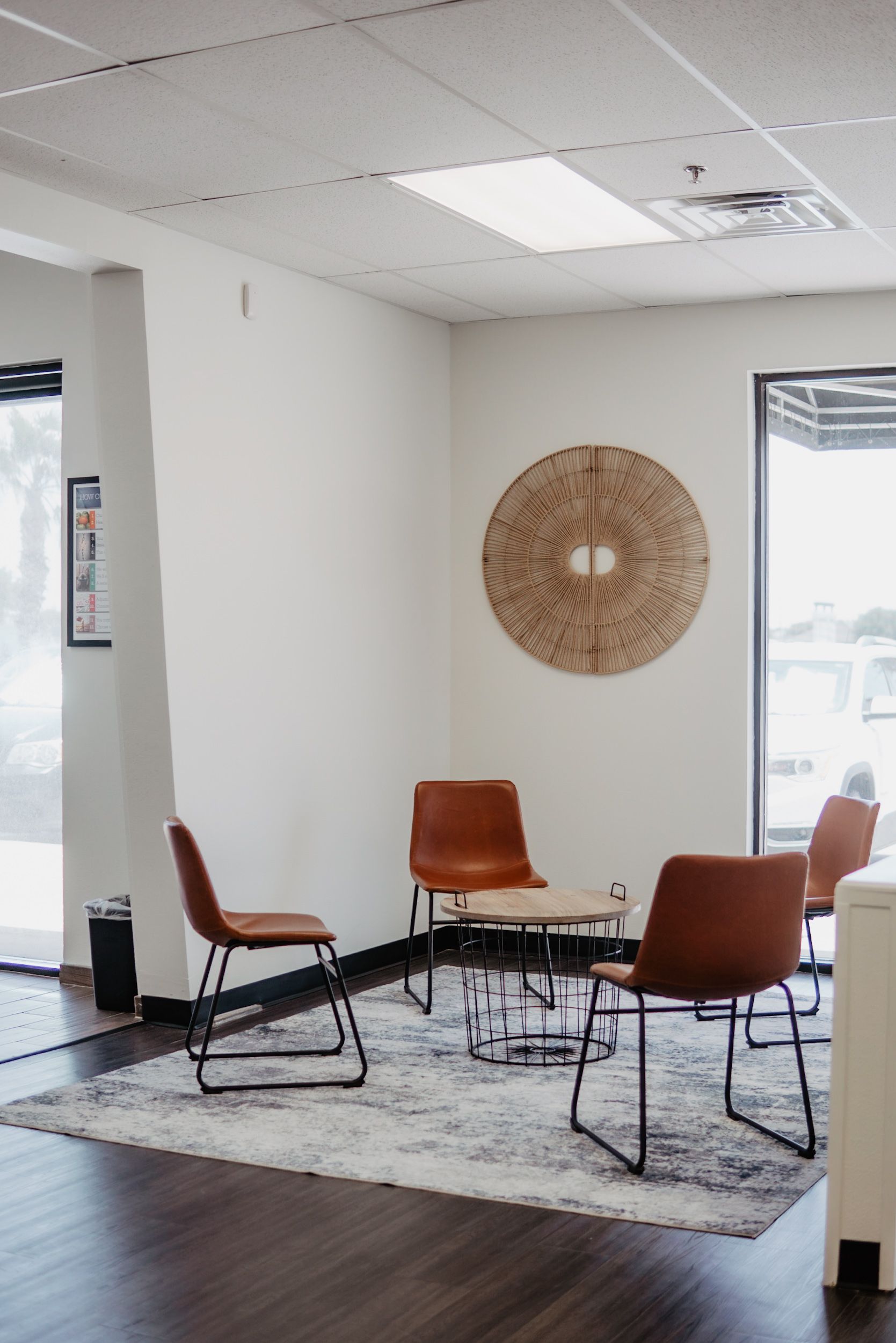 A waiting room with chairs , a table and a rug.