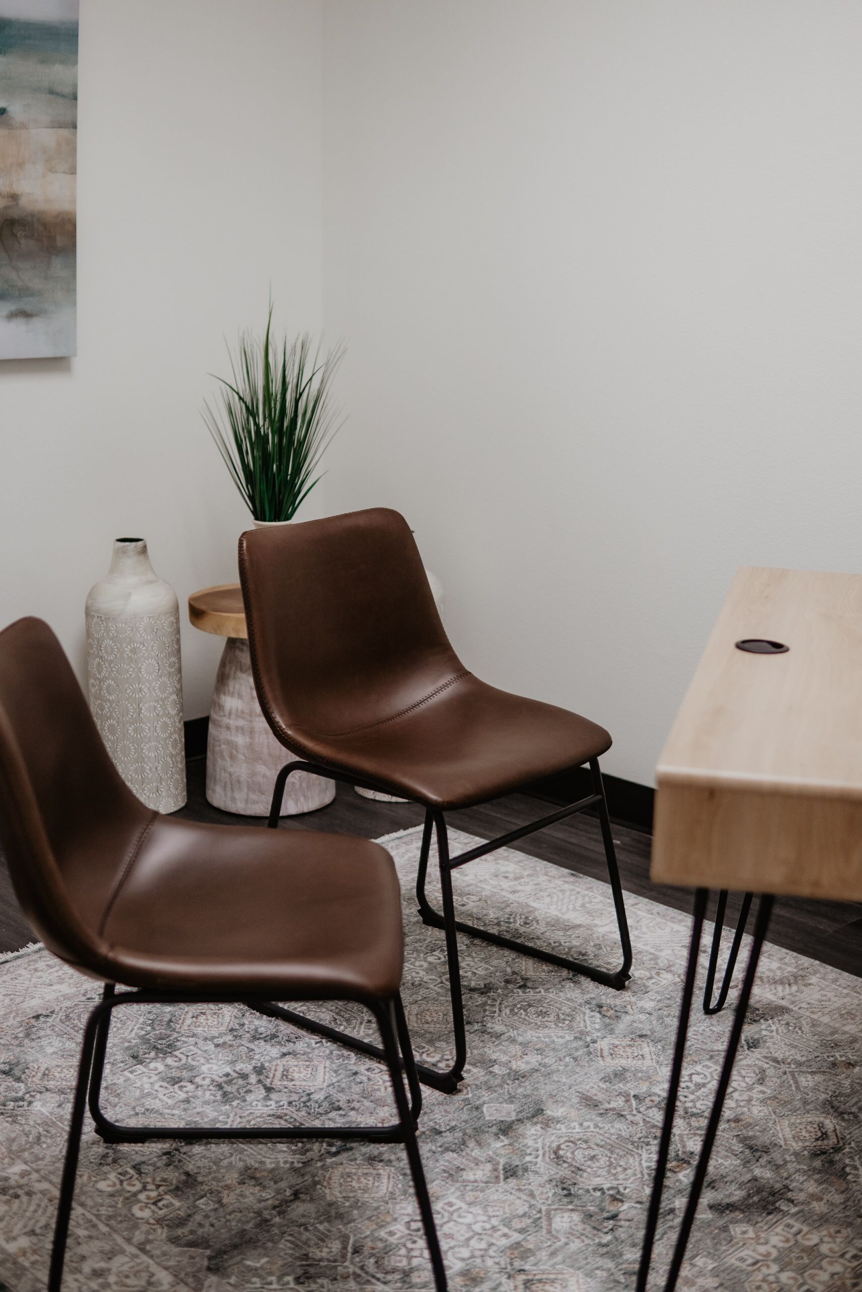 Two brown chairs are sitting next to a wooden desk in a room.