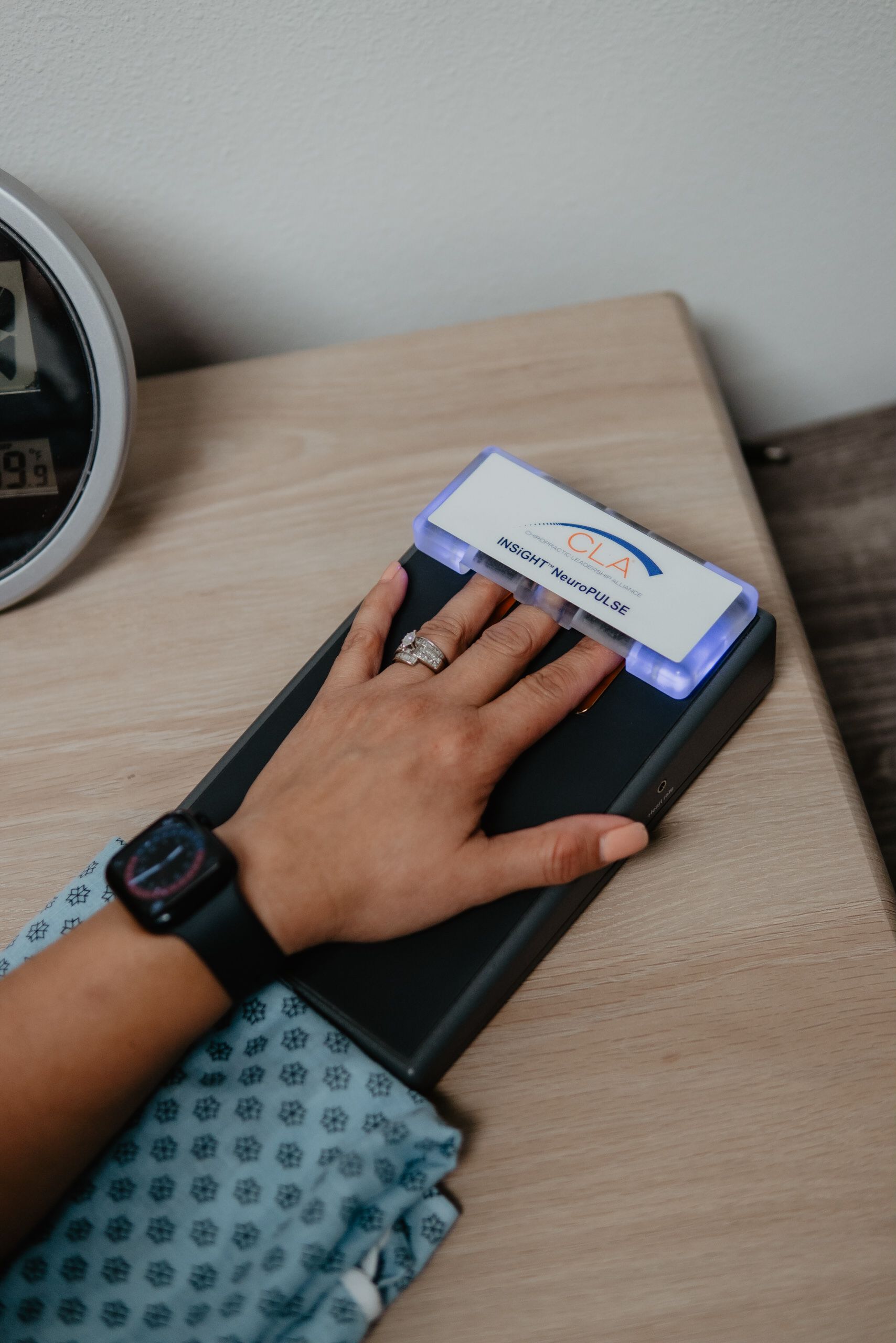 A person wearing a watch is using a device on a table.