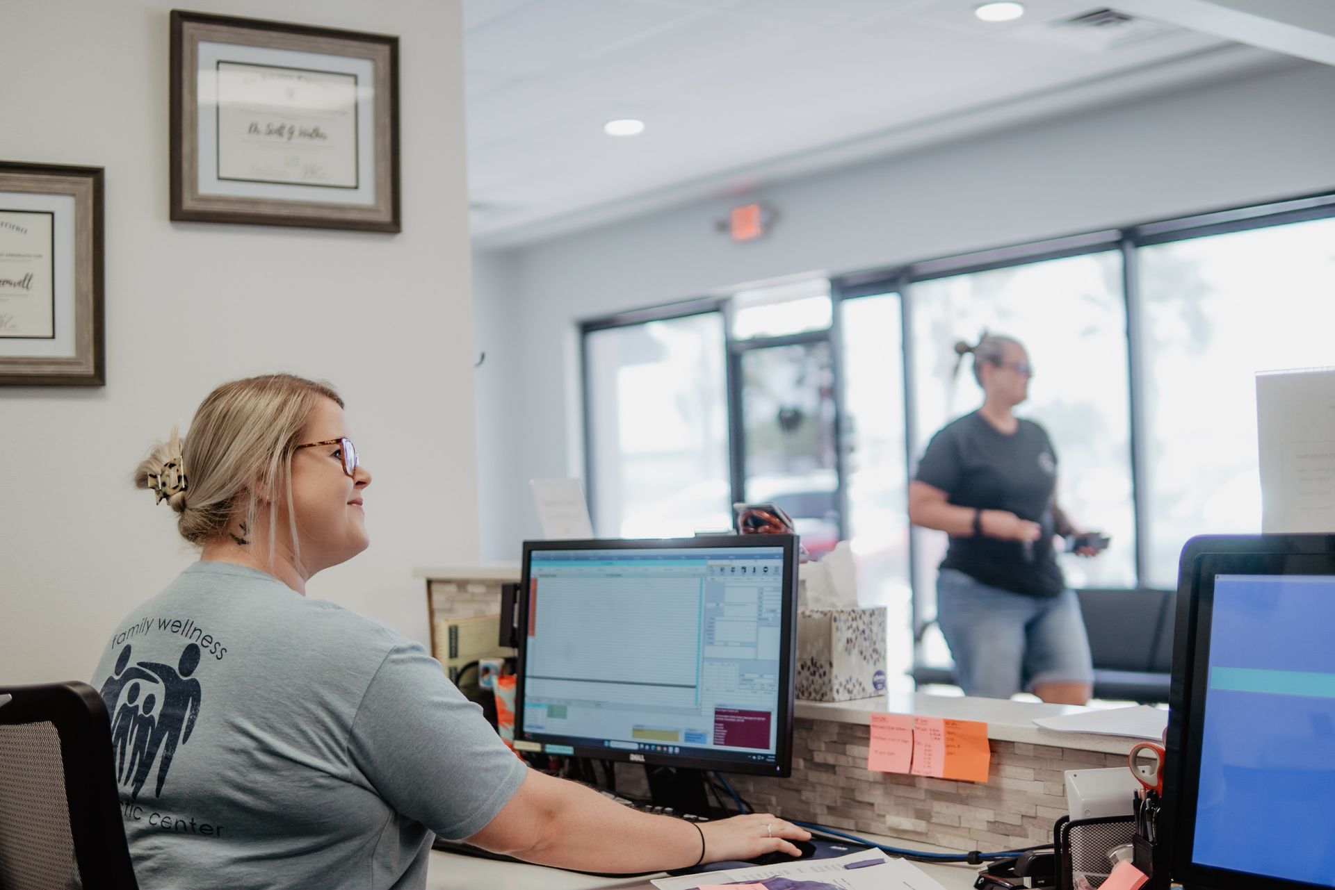 A woman is sitting at a desk in front of a computer.