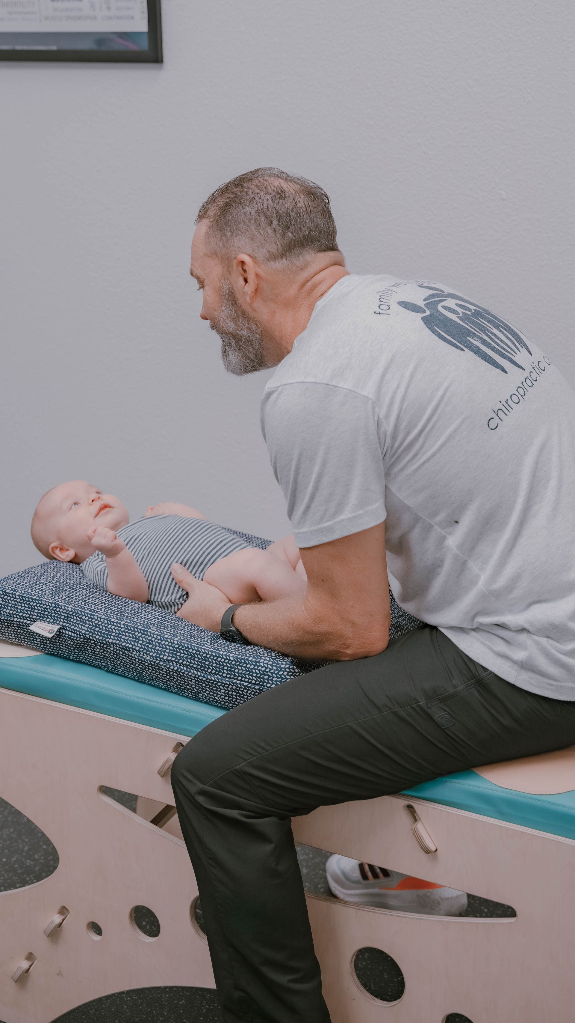 A man is sitting on a table with a baby on it.