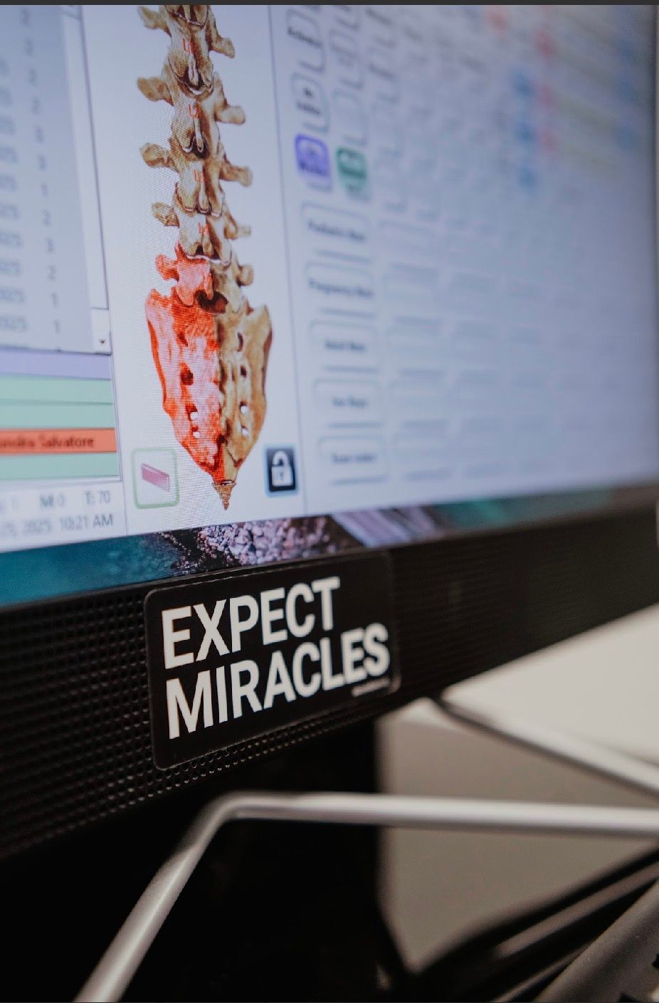 A woman is sitting at a desk using a computer with a certificate on the wall above her
