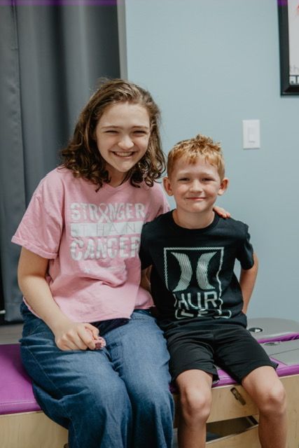 A girl and a boy are sitting next to each other on a bench.