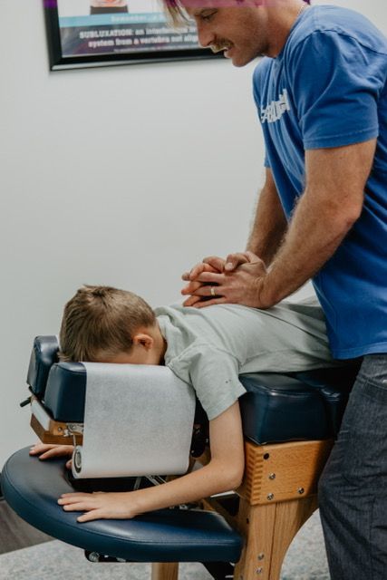 A man is giving a young boy a massage on a table.