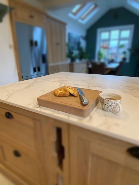 Oak chopping board on kitchen island with croissant and coffee