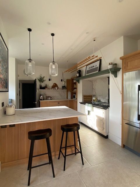 Oak kitchen with peninsula, black bar stools and aga