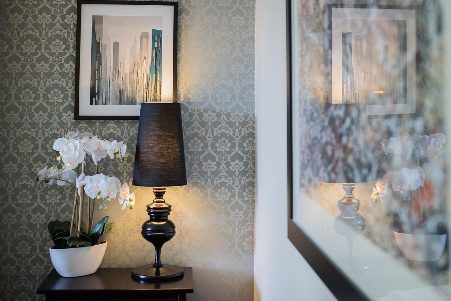 Tall black table lamp with white orchid and Jackson Pollock print