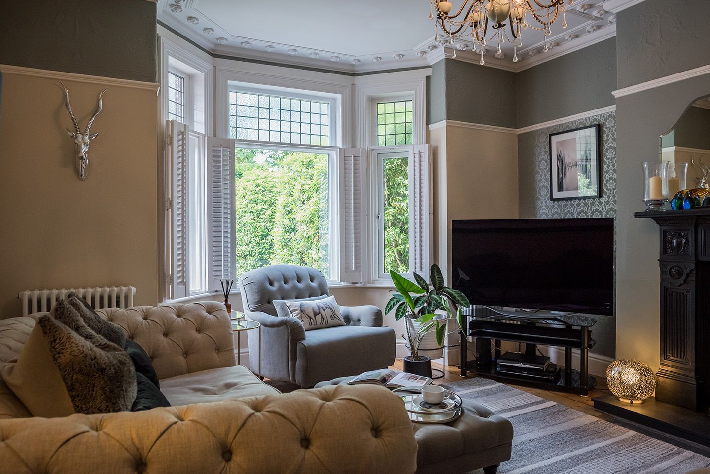 Living room with earthy tones, grey accent chair in bay window with shutters