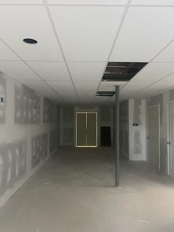 Construction site interior with drywall, drop ceiling, and open ceiling panels; unfinished.