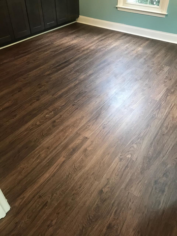 Dark wood-look flooring in a room with dark cabinets and blue walls.