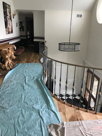 Interior view of a home with a balcony and hardwood floors. A hanging light fixture and black and white checkered floors are visible.