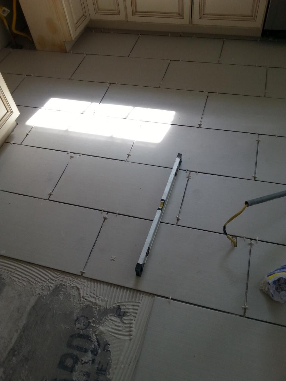 Newly installed gray floor tiles with a level and tools.
