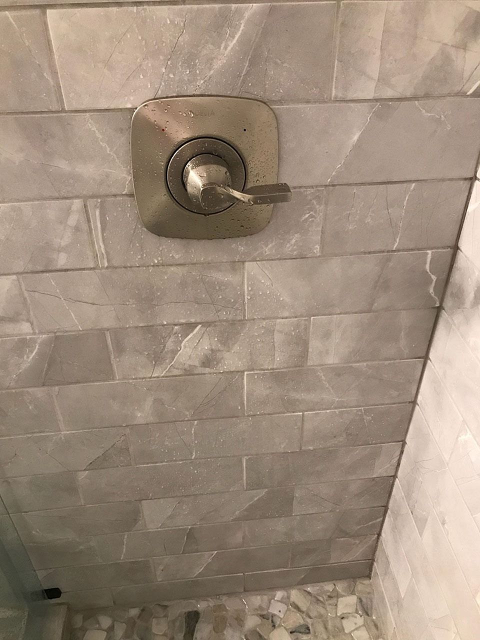 Shower faucet on gray tile wall.