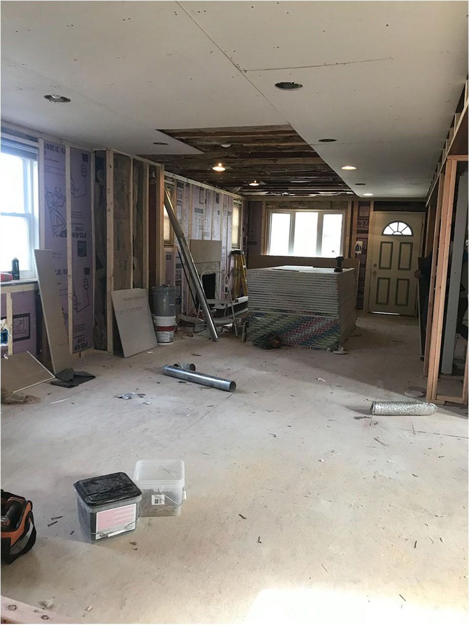 Interior of a home under construction; exposed framing, drywall, and ceiling damage.