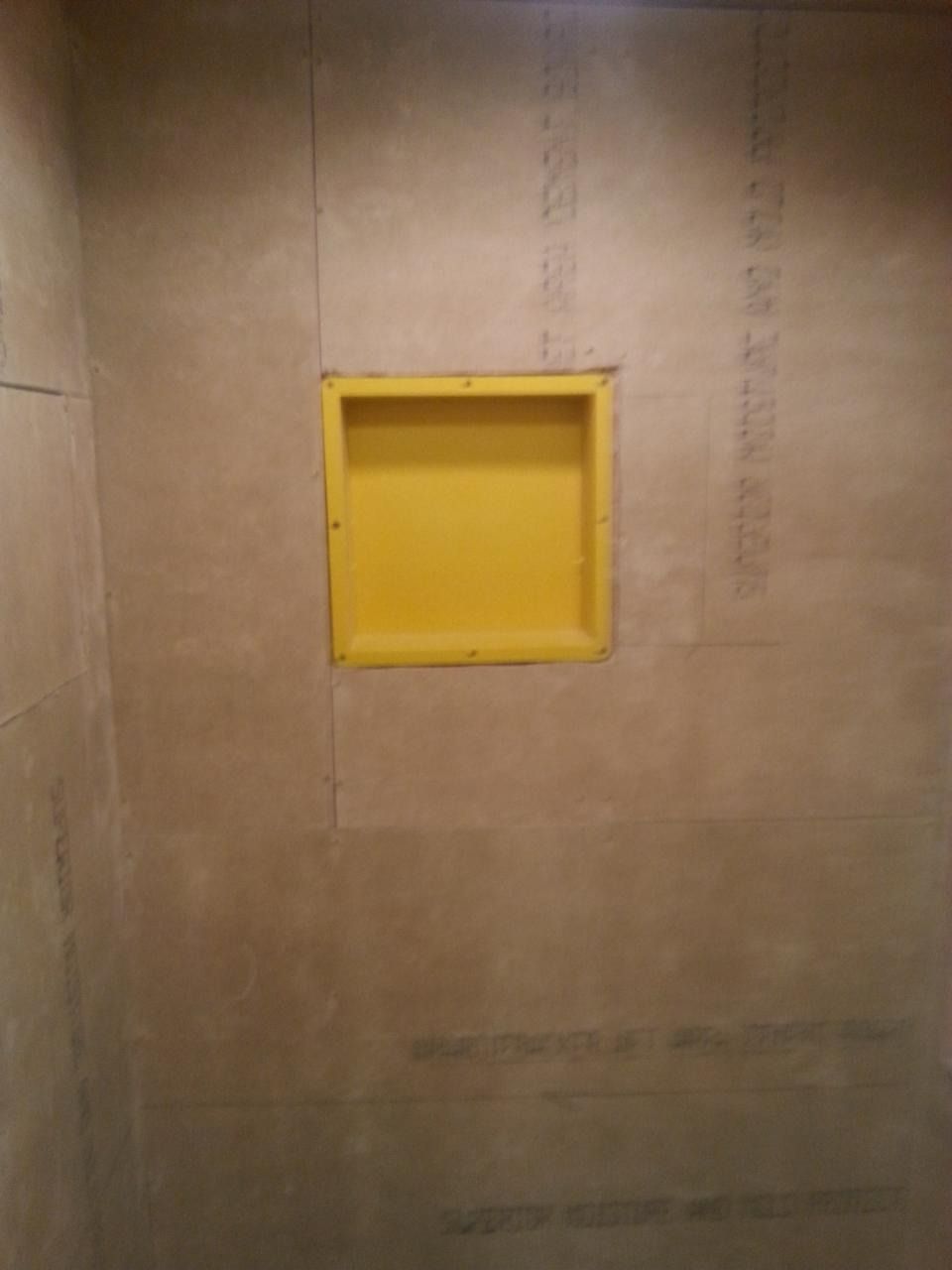 Yellow shower niche in a tile wall.