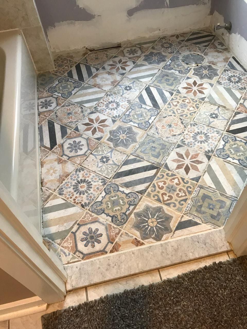 Tiled bathroom floor with various patterns and colors, viewed from above.